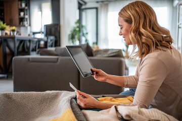 Woman booking travel using tablet and credit card at home
