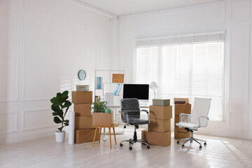 Moving day. Cardboard boxes, computer and furniture in office