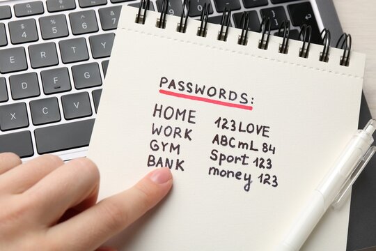 Woman reading passwords written in notebook at table, top view