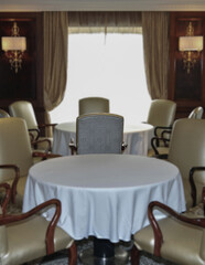 Formal elegant restaurant dining room onboard luxury cruiseship or cruise ship liner with set tables, ocean views and impressive interior inside architecture chandelier