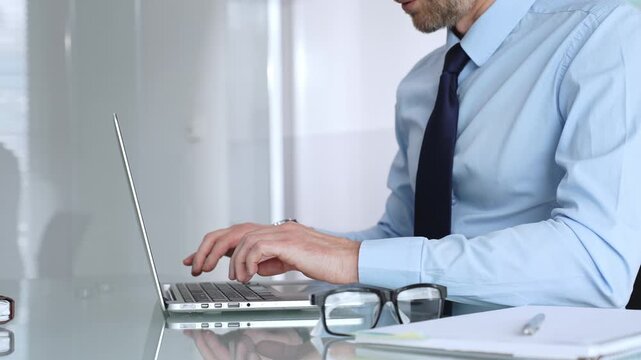 Businessman working on laptop in office, typing keyboard, focusing on professional corporate tasks. Business people concept