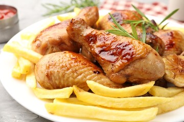 Grilled chicken drumsticks with french fries and spices on table, closeup