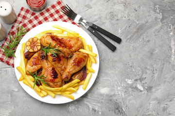 Grilled chicken drumsticks served with french fries and spices on grey table, flat lay. Space for text