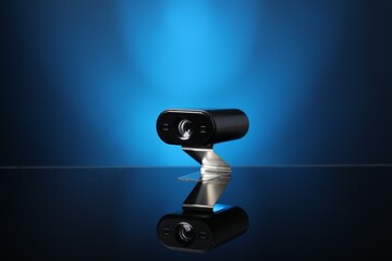 Modern hidden spy camera on mirror surface against blue background, closeup