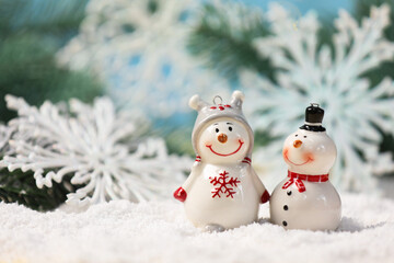 Cute decorative snowman on artificial snow against blurred background, closeup. Space for text