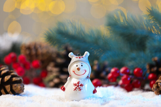 Cute decorative snowman on artificial snow against blurred background, closeup - Powered by Adobe