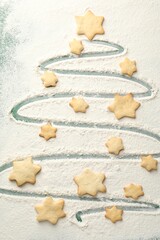 Christmas tree shape made with flour and cookies on green background, flat lay