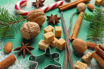 Christmas composition with cookie cutter, fir tree branches and spices on green background, closeup