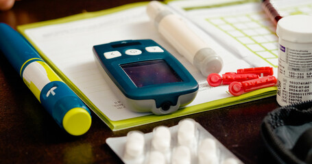 A person uses a glucometer to monitor blood sugar levels in their living room. Nearby, medications...