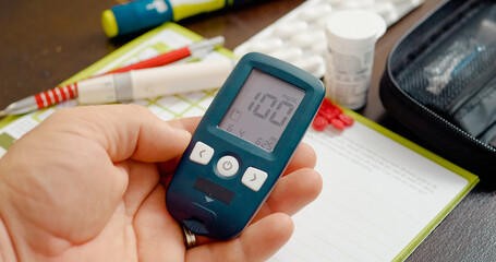 A glucometer displays a reading of, indicating a slightly elevated blood sugar level. The individual takes notes and considers dietary changes for better health management.