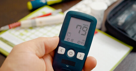 A person checks their blood sugar using a glucometer, revealing a normal reading of 79 mg. This reflects effective management of glucose levels at home.