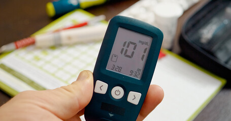 A person checks their blood sugar using a glucometer, revealing a healthy, normal glucose level of 101. Test supplies are neatly arranged on the table.