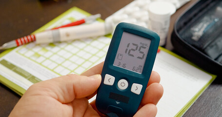 Glucometer displays a blood sugar level of 125 mg dL, indicating a borderline result. Monitoring is...