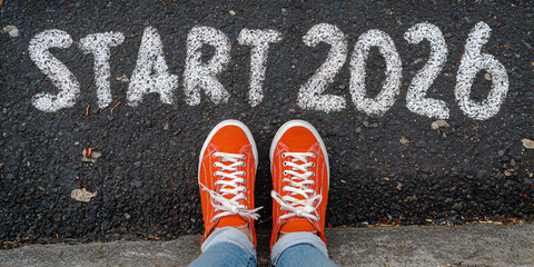 Beginning of New year 2026, Top view of orange sneakers on asphalt with start 2026 painted in white, signifying the commencement of a new year and the pursuit of aspirations