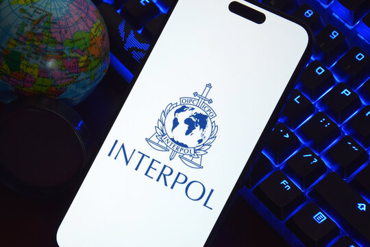 The smartphone with Interpol logo displayed on screen. International Criminal Police Organization or Interpol.