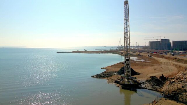 Large crawler crane working at a construction site by the sea,