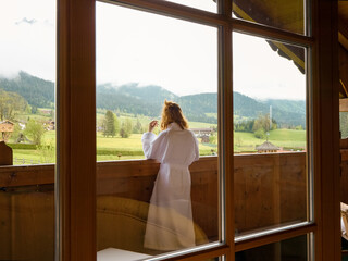 Obraz premium Calm and relaxed woman enters the room from the balcony. Female beginning her day after receiving fresh air.