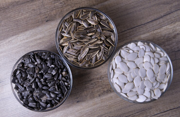 Various seeds in glass bowls on a wooden table.