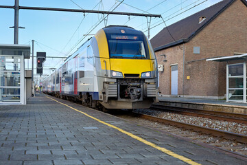 Modern electric passenger train at a European station platform under a clear blue sky. Highlighting efficient public transport, travel, and urban infrastructure.