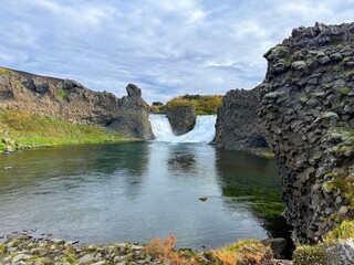 Hj&aacute;lparfoss Waterfall in South Iceland, a Scenic Natural Wonder Surrounded by Volcanic Rocks and Flowing River