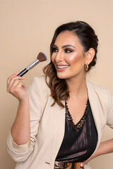 Obraz premium Professional makeup artist posing with brush on beige background