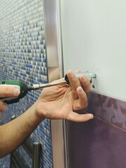 Man drilling a hole in the tile of bathroom