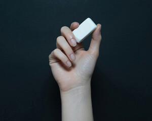 Gentle hand holding a white eraser against a dark background, symbolizing correction and new beginnings in learning or projects