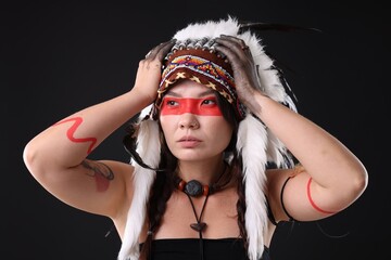 Shaman woman in native American Indian headdress with face painting on black background
