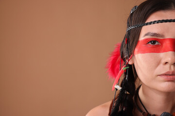 Shaman woman with face painting on pale brown background, closeup. Space for text