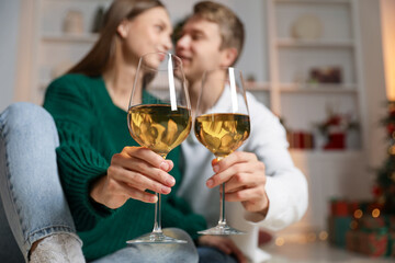 Lovely couple with glasses of wine in festive decorated room, selective focus