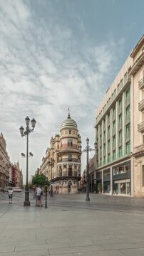 Pedestrians walking along Avda. de la Constitucion, major avenue in Casco Antiguo district of Seville, Spain. Timelapse hyperlapse with Edificio de la Adriatica, historical buildings and passing trams