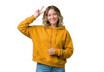 Young woman wearing a yellow hoodie and jeans, making a peace sign and giving a thumbs up, isolated on transparent background