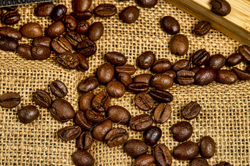Detailed macro image of roasted coffee beans on burlap fabric with rich brown tones and natural light. Perfect for cafe branding, beverage visuals, and rustic backgrounds