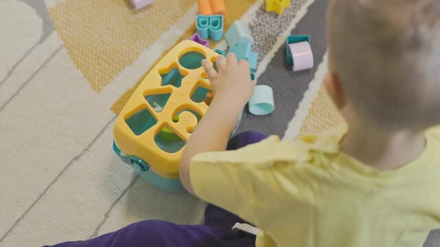 Little toddler playing with educational shape sorter toy