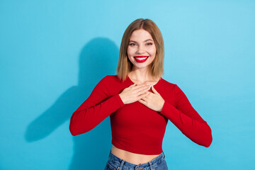 Young smiling woman in red top on blue background conveys happiness and positivity through her...