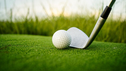 Golf clubs and balls on a green lawn in a beautiful golf course with morning sunshine.