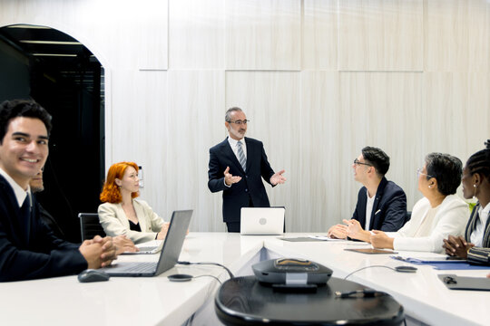 Group of diverse businesspeople at conference, happy business workers discussing and brainstorming together at meeting room. Cheerful officers exchange ideas and listen to presentations during meeting - Powered by Adobe