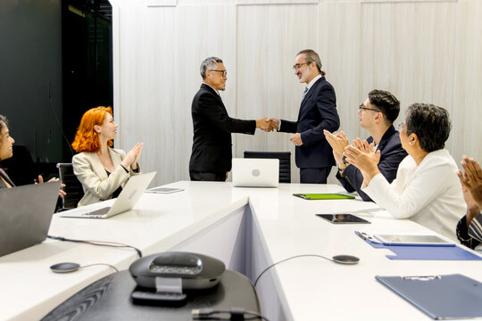Group of diverse businesspeople at seminar conference, cheerful officers listen to presentation during meeting. Audiences clapping hands while businessmen having handshake after finish business deal.