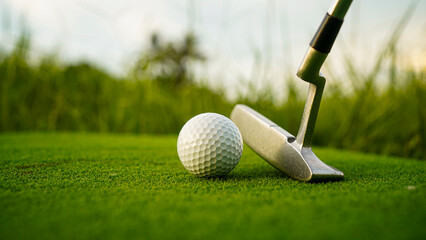 Golf clubs and balls on a green lawn in a beautiful golf course with morning sunshine.