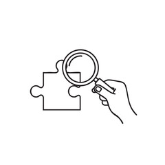 Hand holding a magnifying glass over a puzzle piece outline