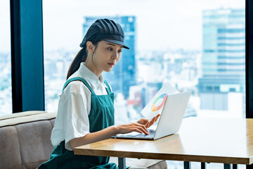 パソコン作業をするエプロンをつけた女性スタッフ