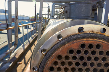 Pipe tube sheet or plate of heat exchanger or boiler part with flange closeup corrosion texture over out of focus petrochemical industrial background with sunflares. Trypophobia concept.