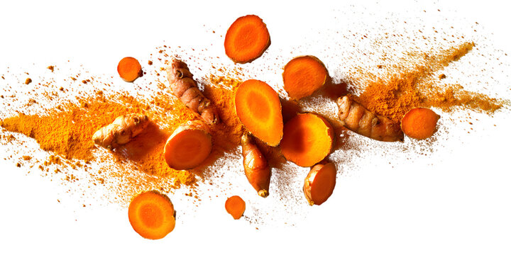 Exploding turmeric root and slices with powder against black background
