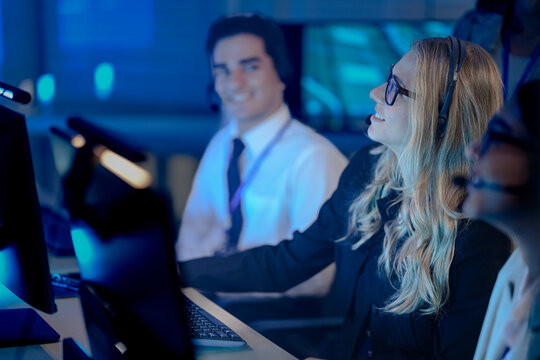 Command center lead focused intense monitoring critical systems late night headset connects team analyzing real time data screen crucial vigilance protects infrastructure operation underway.