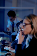 Focused male team leader headset on points screen provides clear direction colleagues late night modern tech hub achieving operational goals project success now leadership guides team forward boost.