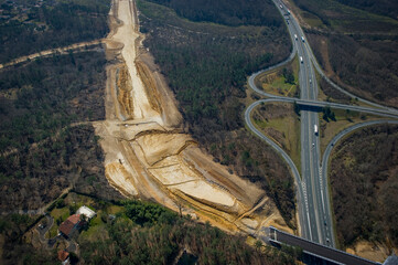 Construction crews work on a high-speed train line in France, creating a path through the landscape while a highway runs parallel.
