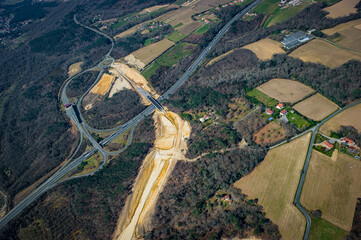 Construction crews work on a high-speed train line in France, creating a path through the landscape while a highway runs parallel.