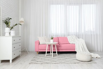 Interior of light living room with pink sofa