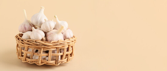 Wicker basket of fresh garlic on beige background with space for text