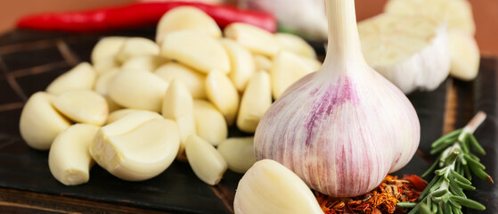 Wooden board with fresh garlics and rosemary on brown background, closeup